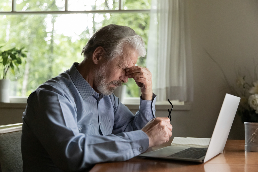 Older man having difficulty reading his computer because of cataracts