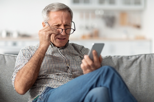 Older man having trouble reading phone because of cataracts