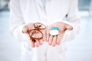 Doctor holding a pair of eyeglasses and contact lenses