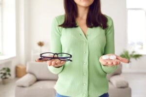 Woman holding eye glasses and contact lenses while considering LASIK surgery