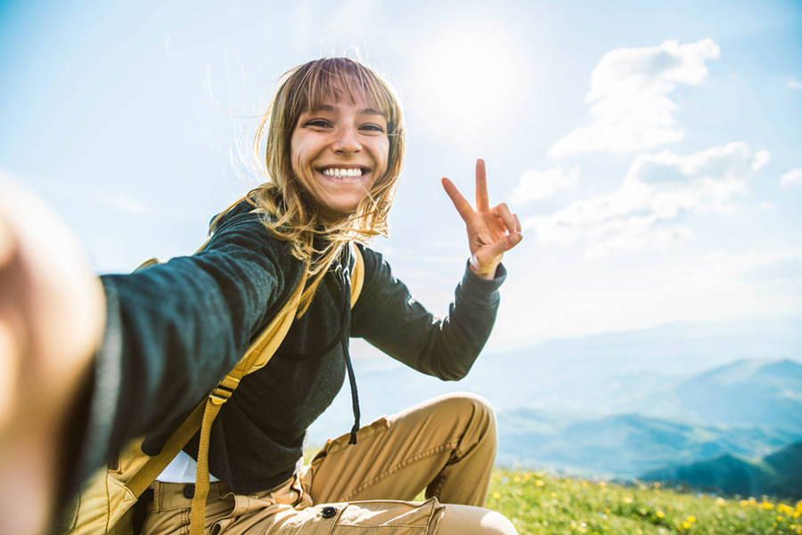 Young woman taking selfie portrait hiking mountains